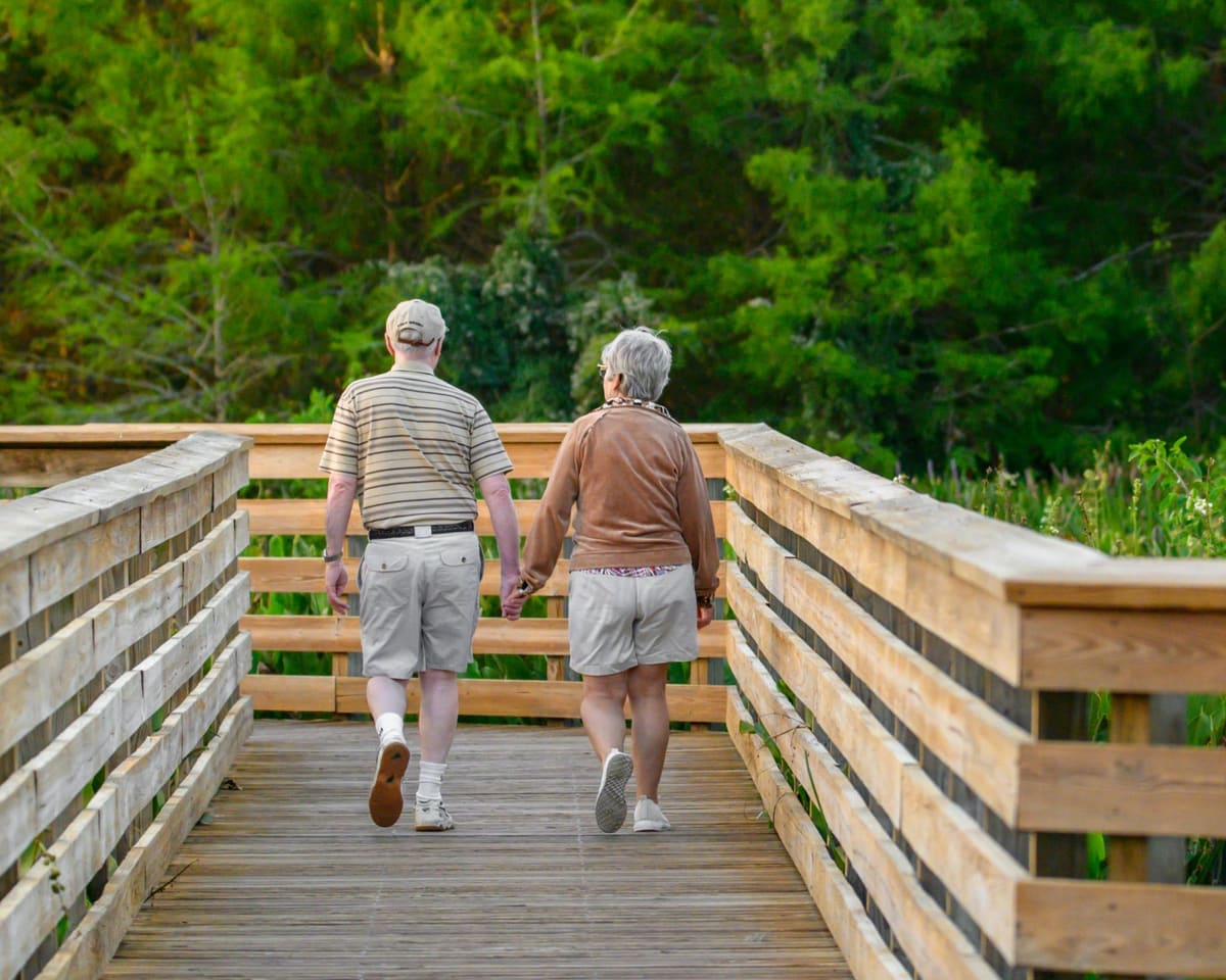 A senior couple holding hands on a boardwalk through the Texas Hill Country near Georgetown